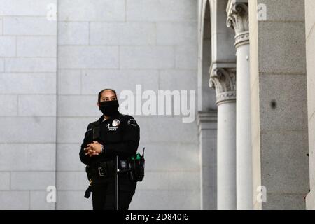 Los Angeles, États-Unis. 27 octobre 2020. Un policier portant un masque facial tient un garde à l'hôtel de ville de Los Angeles à Los Angeles, aux États-Unis, le 26 octobre 2020. Le comté de Los Angeles, le comté le plus peuplé des États-Unis, a vu ses cas de COVID-19 dépasser 300,000 et le nombre de morts a atteint 7,000 lundi. Credit: Xinhua/Alay Live News Banque D'Images