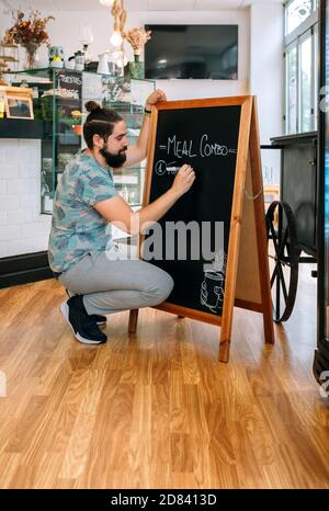 Un jeune serveur rédige le menu du jour Banque D'Images