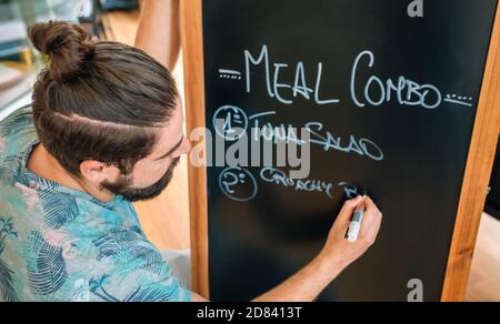 Gros plan du jeune serveur qui écrit le menu du jour Banque D'Images