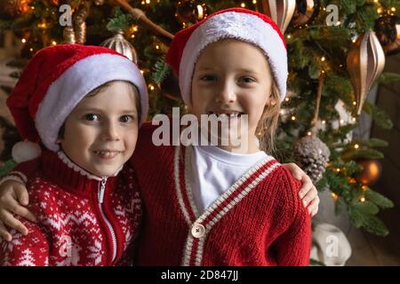 Portrait de petits enfants souriants posé près de l'arbre de Noël Banque D'Images