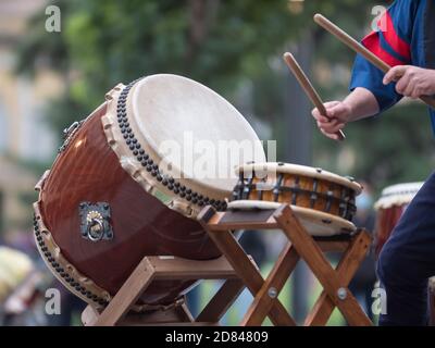 Homme jouant des tambours de la tradition musicale japonaise lors d'un événement public en plein air. Banque D'Images