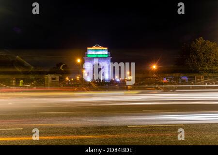 Vue sur les pistes lumineuses de véhicules la nuit en face de l'emblématique monument de la porte de l'Inde dans le centre de Delhi. Banque D'Images