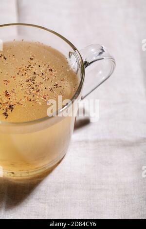 Bouillon d'os de légumes frais dans une tasse de verre avec épices et herbes sur fond textile gros plan. La nourriture saine de régime sont riches en vitamines, collagène et an Banque D'Images