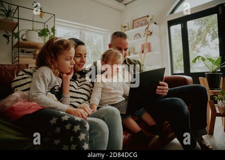 Les jeunes enfants de la famille qui utilisent un ordinateur portable à la maison se détendent table de traitement Banque D'Images