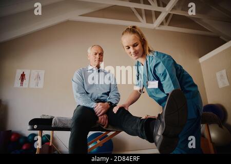 Homme âgé à la retraite faisant des exercices physiques avec l'aide de formateur professionnel Banque D'Images