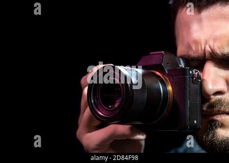La personne tient un appareil photo et est configurée pour la prise de vue. Le photographe regarde dans le viseur de l'appareil photo et prend des photos. L'objet sur un b noir Banque D'Images