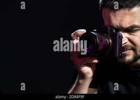La personne tient un appareil photo et est configurée pour la prise de vue. Le photographe regarde dans le viseur de l'appareil photo et prend des photos. L'objet sur un b noir Banque D'Images