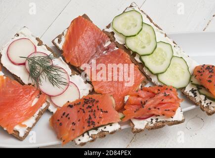 Canapés et sandwichs avec saumon et légumes sur fond de bois Banque D'Images