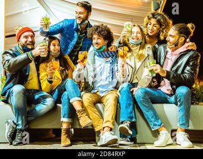 Des amis tendance avec masque pour boire des cocktails à l'extérieur du bar - jeunes étudiants ayant la fête dans la rue - Nouveau concept de divertissement normal avec des amis Banque D'Images