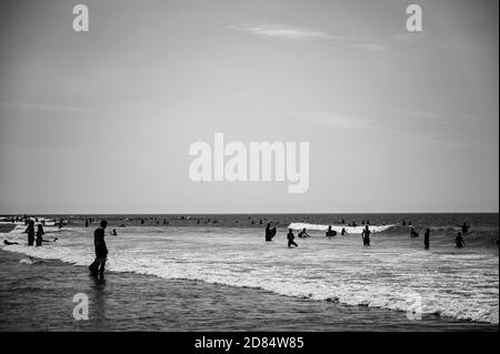 Image monochrome de Surfers jouer au bord de la plage en noir et blanc dans les combinaisons à Croyde Bay, Devon Banque D'Images