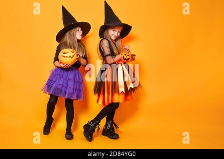 Deux petits sorcières en costumes d'halloween sur fond orange Banque D'Images