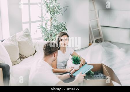 couple ouvrant une boîte en carton dans un nouvel appartement . Banque D'Images