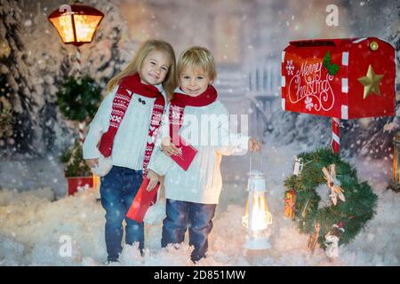 Mignons enfants blonds, garçons et filles, frères et sœurs, poster la lettre de Noël au Père Noël, jour d'hiver enneigé Banque D'Images