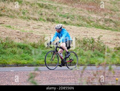 Holyrood Park, Édimbourg, Écosse, Royaume-Uni. 27 octobre 2020. Température de 8 degrés centigrade et ciel gris plomb avant de fortes pluies plus tard au parc dans le centre-ville. Photo : cycliste sur la route à travers le parc. Banque D'Images