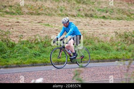 Holyrood Park, Édimbourg, Écosse, Royaume-Uni. 27 octobre 2020. Température de 8 degrés centigrade et ciel gris plomb avant de fortes pluies plus tard au parc dans le centre-ville. Photo : cycliste sur la route à travers le parc. Banque D'Images