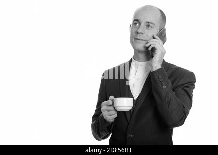 Heureux réfléchis pygargue à tête Caucasian businessman smiling and talking on mobile phone while holding Coffee cup Banque D'Images