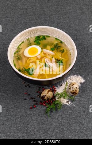 Soupe de poulet avec nouilles et œuf dans un bol en carton pour emporter ou livraison de nourriture isolée sur fond blanc. Banque D'Images