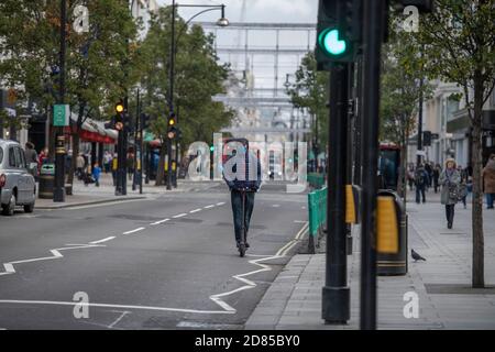 Triporteur électrique avec masque de visage voyageant le long d'Oxford Street à Londres avec 2020 installations de lumière de Noël en hauteur, 26 octobre 2020. Banque D'Images