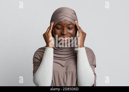 Concept de mal de tête. Triste Noire musulmane Dame dans hijab souffrant de douleur de Migraine Banque D'Images