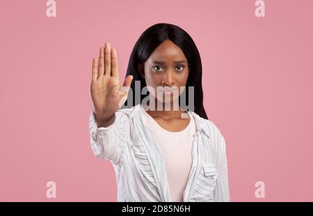 Merci mais aucun concept. Femme noire sérieuse faisant un geste d'arrêt sur fond rose studio Banque D'Images