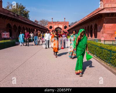 Agra, Uttar Pradesh, Inde - Mars 2019: Un groupe de touristes indiens dans une tenue colorée marchant à l'intérieur de l'entrée en grès rouge du Taj Mahal. Banque D'Images