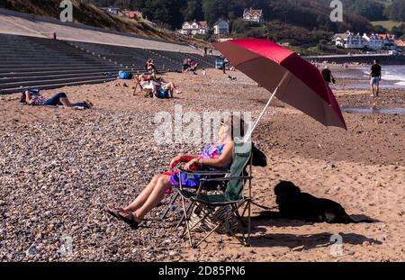 Femme se reposant sur une chaise en été sur la plage, Whitby, Angleterre, Royaume-Uni Banque D'Images