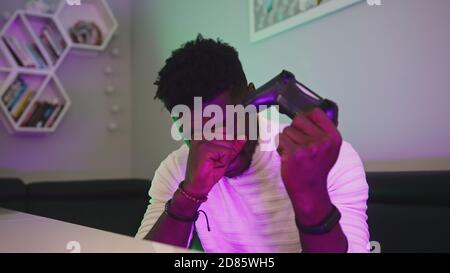 Homme noir jouant à un jeu à l'aide de la console de commande du joystick. Divertissement pendant le maintien. Partie perdue. Photo de haute qualité Banque D'Images