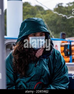 Femme portant un masque facial et un imperméable, Wroxham, Norfolk, Angleterre, Royaume-Uni Banque D'Images