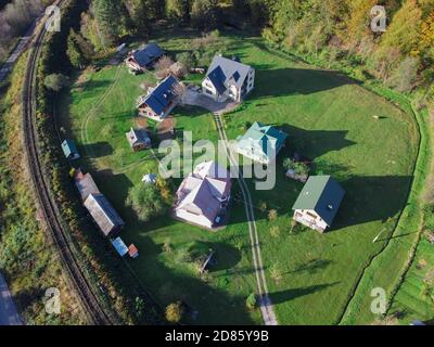 Maisons sur une pelouse verte au pied de la montagne près des voies ferrées. Vue de dessus du village Banque D'Images
