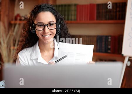 Femme en lunettes assise au bureau, ayant un magnétoscope sur ordinateur portable Banque D'Images