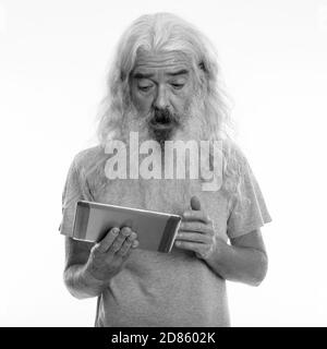 Studio shot of senior homme barbu using digital tablet while looking choqué Banque D'Images