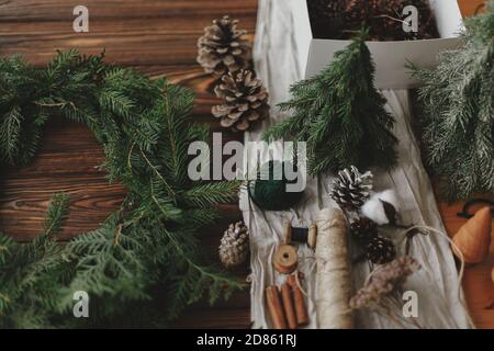 Fabrication d'une couronne de noël rustique sur une table en bois. Couronne de Noël avec baies, branches vertes, cônes de pin et décorations de fête naturelles, ciseaux, t Banque D'Images