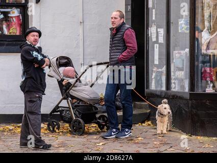 Deux hommes avec poussette et chien par magasin Banque D'Images
