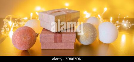 Boules de Noël, boîtes-cadeaux sur table dorée et guirlande lumineuse avec espace de copie sur fond doré.Décoration de Noël dorée avec boîtes-cadeaux, boules a Banque D'Images