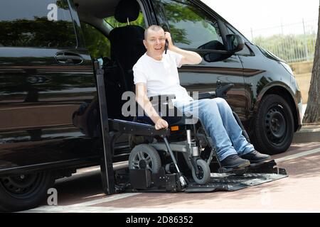 Les personnes handicapées en fauteuil roulant sur l'homme debout sur la voiture ascenseur Banque D'Images