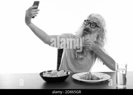Joyeux homme barbu senior souriant en prenant le selfie tout en tenant verre de bière Banque D'Images