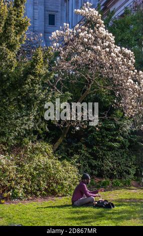 Londres, Royaume-Uni - 21 avril 2019 : UN homme s'assoit et se détend sur une pelouse verte dans un parc. Après-midi d'été dans le parc. Aucune mise au point, en particulier. Banque D'Images