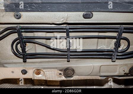 Conduites de carburant noires montées sous le châssis de la voiture, vue depuis le bas de la voiture sur un cric dans un atelier de voiture. Banque D'Images