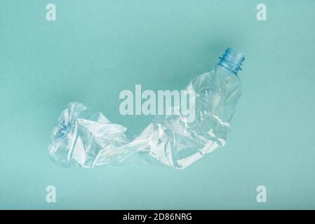 Bouteille en plastique écrasée utilisée sur fond bleu. Banque D'Images