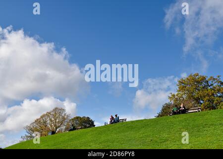 Les gens au sommet d'une colline herbeuse donnent sur une vue Banque D'Images