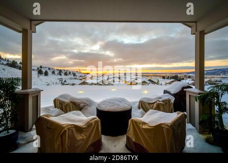 Vue sur le coucher du soleil depuis un patio couvert dans une subdivision au sommet d'une colline de la vallée et du centre-ville de Spokane, Washington, tôt le soir couvert de neige. Banque D'Images