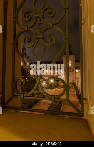 Des étoiles éclatées dans la cour à travers une porte en fer forgé méditerranéenne très ornée Et les styles architecturaux de la renaissance coloniale espagnole mis en valeur par le soir Banque D'Images