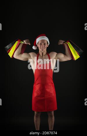 Achats de puissance. Sac à papier de bonne tenue de père noël fléchissant les bras musclés. Achats de vacances. Lendemain de Noël. Boutique de fitness. Noël et nouvel an. Vente et achat. Banque D'Images