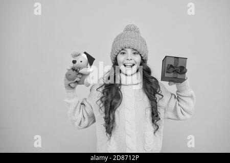 une petite fille tient le jouet de souris et la boîte de cadeau. enfant tricoté vêtements jouer avec le rat jouet. magasin de jouets pour les enfants. noël est ici. noël préféré vacances d'hiver. heureux nouvel an 2020. cadeau de jouet de père noël mignon. Banque D'Images