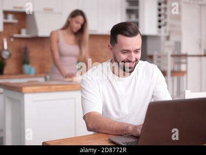 Jeune homme utilise en cuisine accueil ordinateur portable Banque D'Images