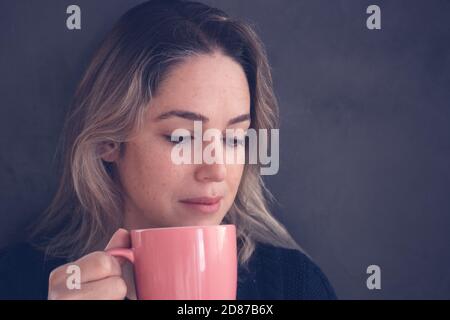 femme regardant la caméra et souriant sur un gris mur d'arrière-plan Banque D'Images
