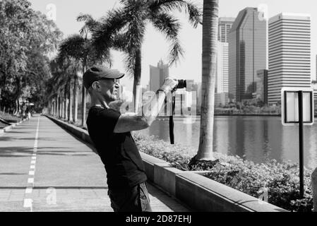 Voir le profil de hauts man touristiques tout en prenant des photos au parc paisible à Bangkok en Thaïlande Banque D'Images