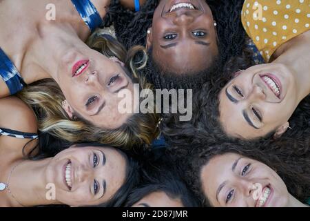 Un groupe de six amis souriants qui se coutent et regardent vers le haut de la caméra Banque D'Images