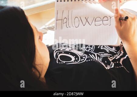 fille couché sur le canapé écrivant halloween dans un bloc-notes Banque D'Images