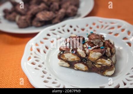 Dessert sicilien typique : un morceau de nougat fait avec des amandes Avola appelées 'minnulata', sur fond d'amandes caramélisées Banque D'Images